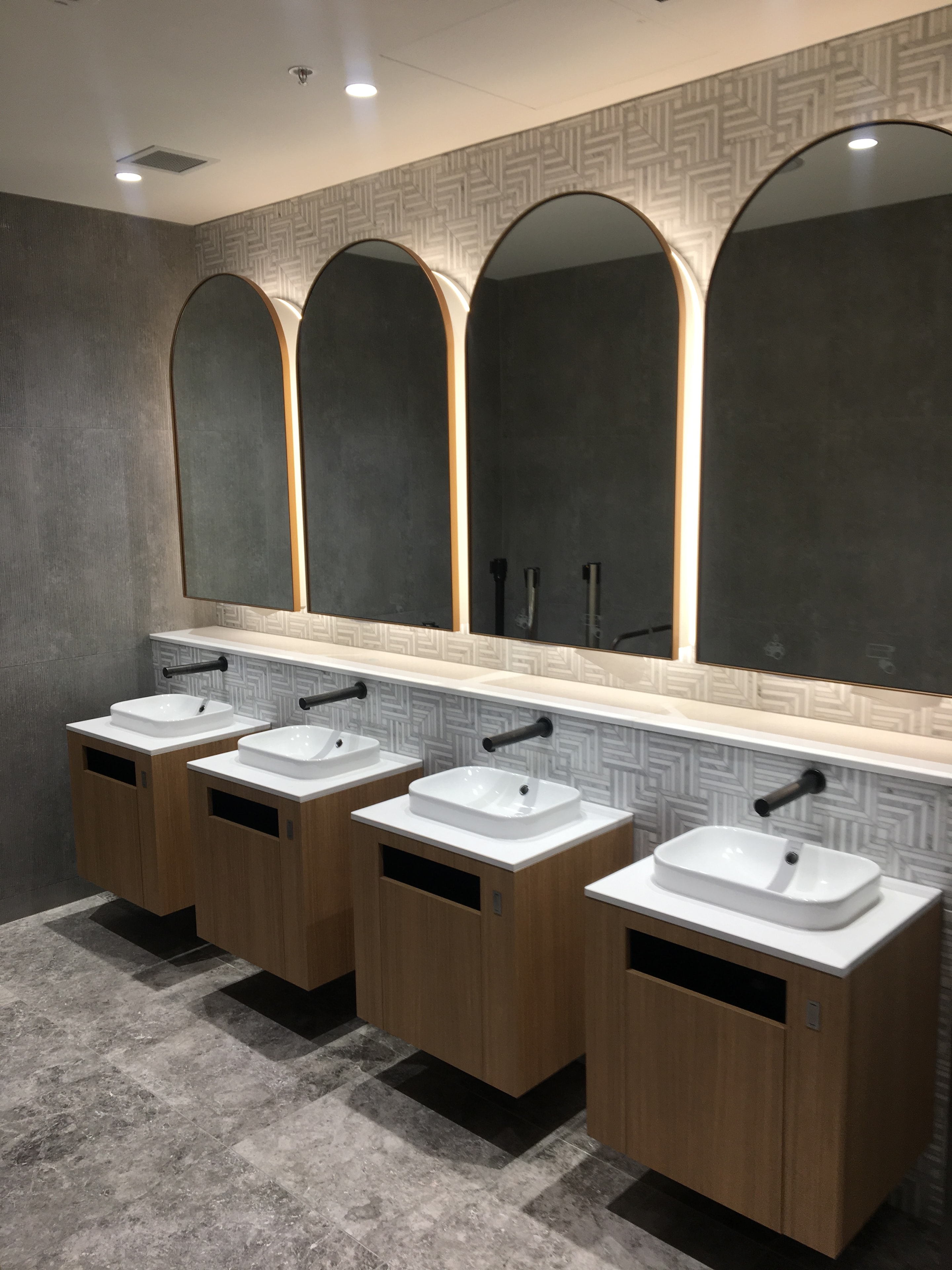 Shopping centre amenities — arched gold-framed mirrors with timber vanity cabinetry